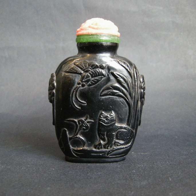 Snuff bottle "jais" sculpted in low relief with a cat looking at a butterfly and other face with two rabbits. Mask on the sides